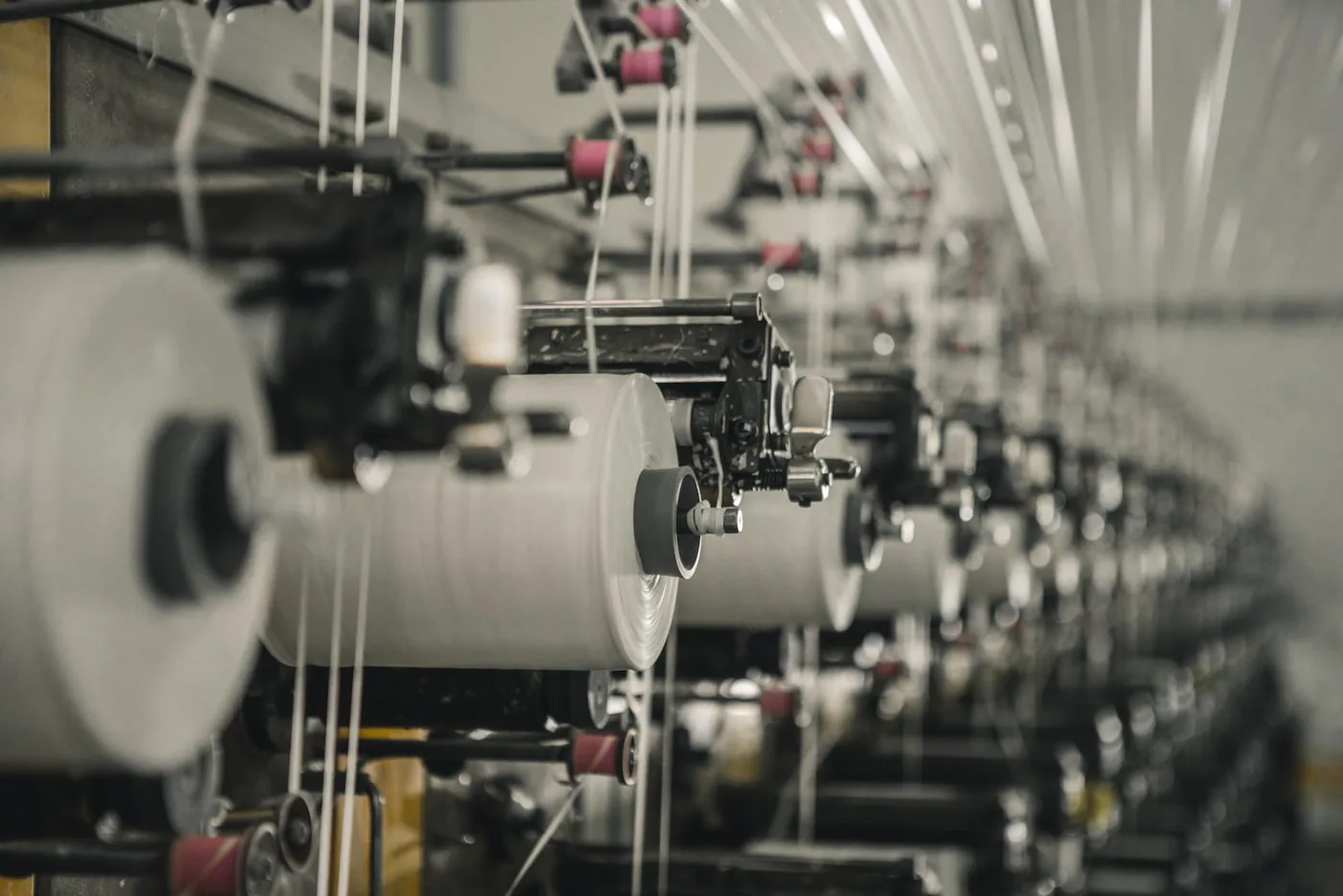Allées de rouleaux de tissus dans un marché textile de Shaoxing, étiquettes de composition apparentes.