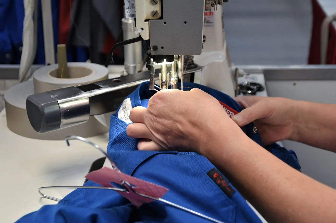 Contrôle en ligne d’une opératrice sur une chaîne de couture, vérifiant les coutures sur un t‑shirt.