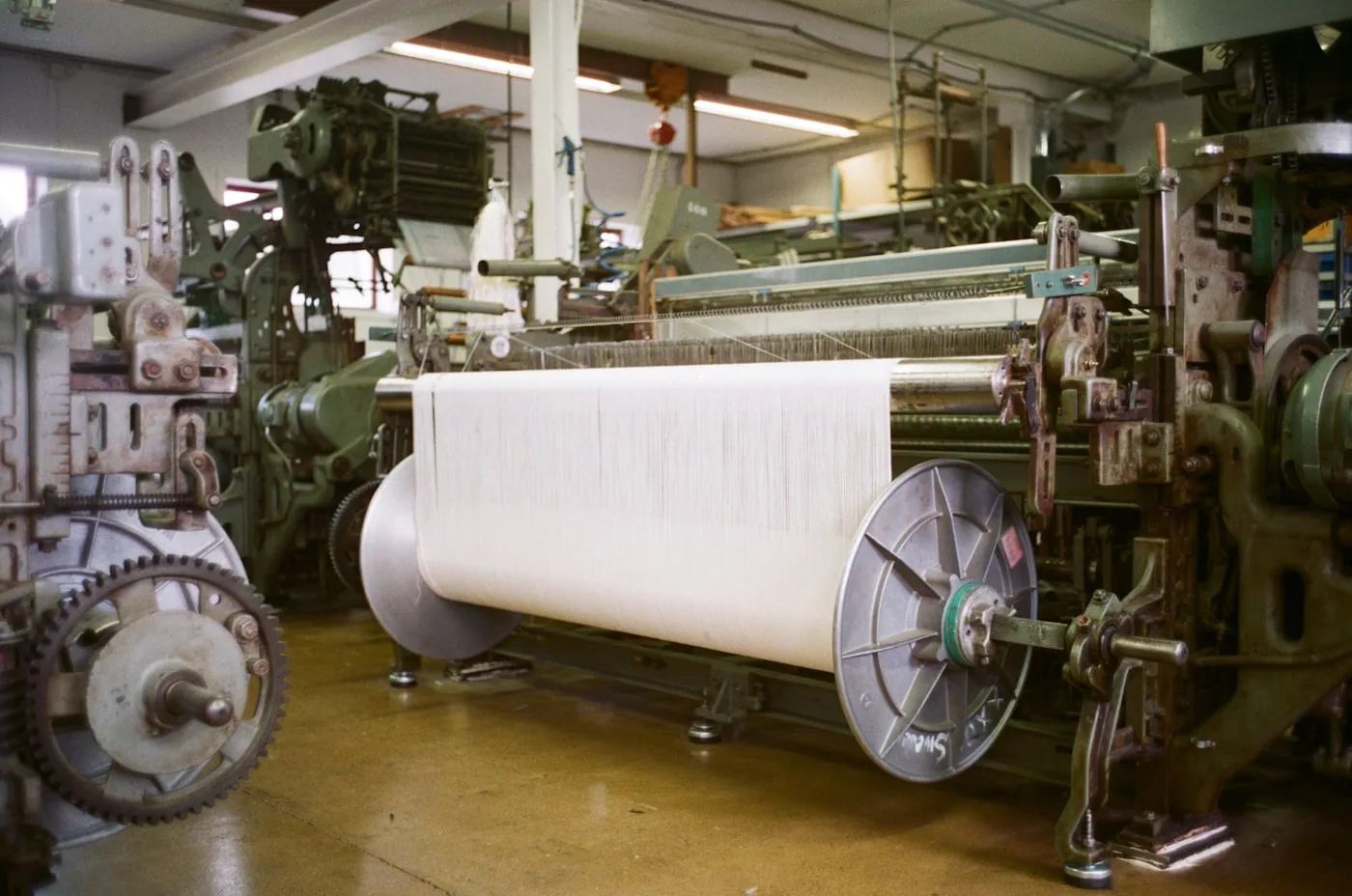 Atelier de tricotage avec des machines à maille circulaires en fonctionnement et rouleaux de fil.