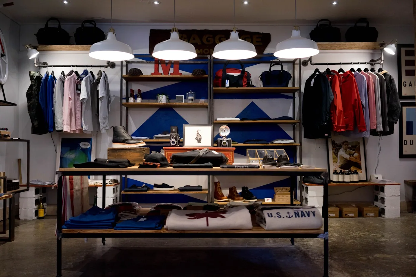Intérieur d’une boutique de vêtements avec cabines d’essayage, portant de vestes et comptoir de caisse.