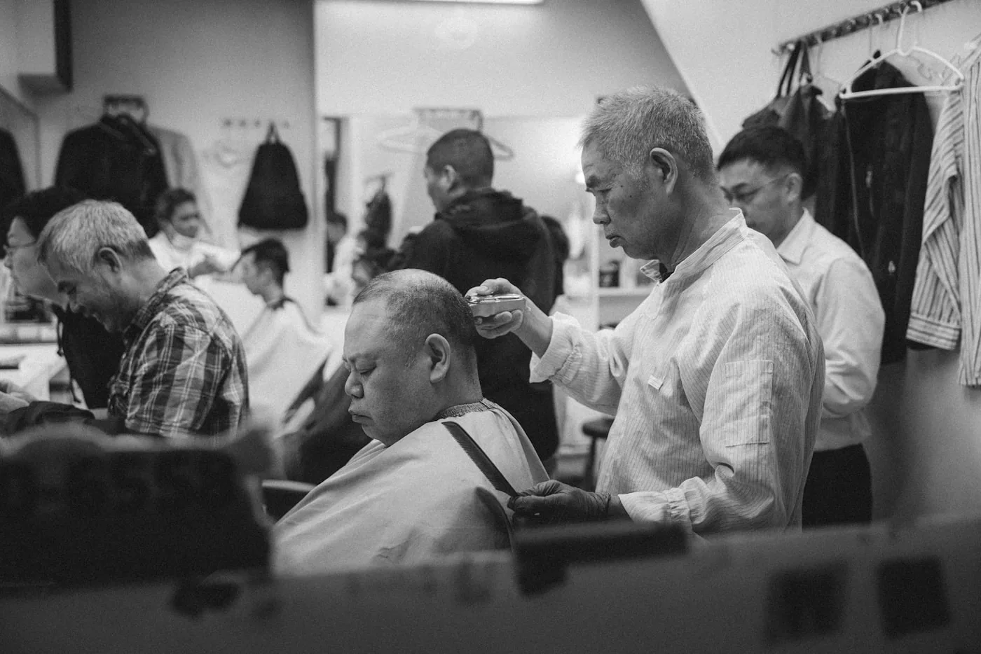 Essayage en atelier : un modéliste ajuste la couture d’épaule sur un mannequin, vérifiant le tombé.