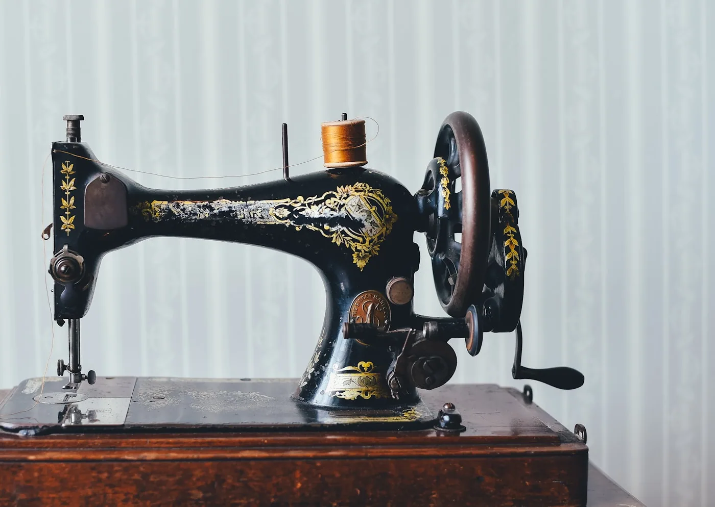 Gros plan d’une machine à coudre réalisant un bartack de renfort sur un passant de ceinture en denim.