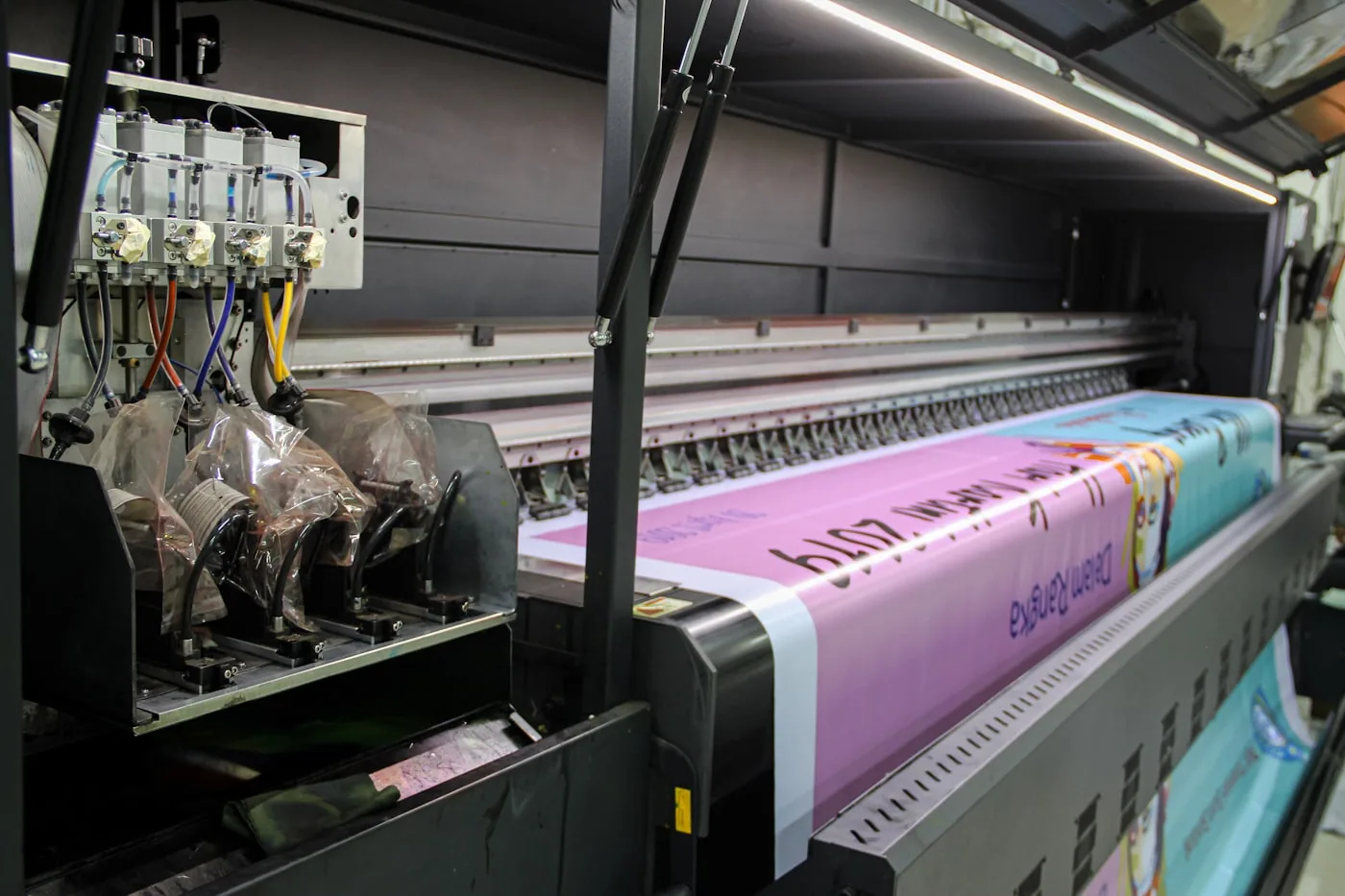 Un atelier d’impression textile rotary avec un rouleau d’impression en action sur une laize de tissu.