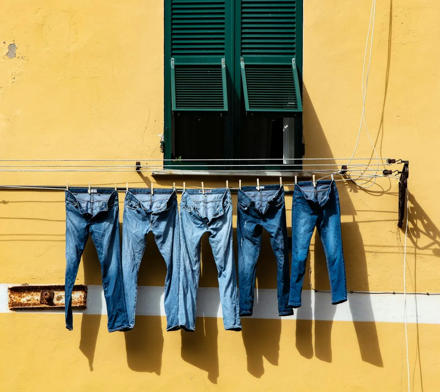 Ligne de délavage denim avec jeans suspendus sur cintres passant dans une cabine de lavage.