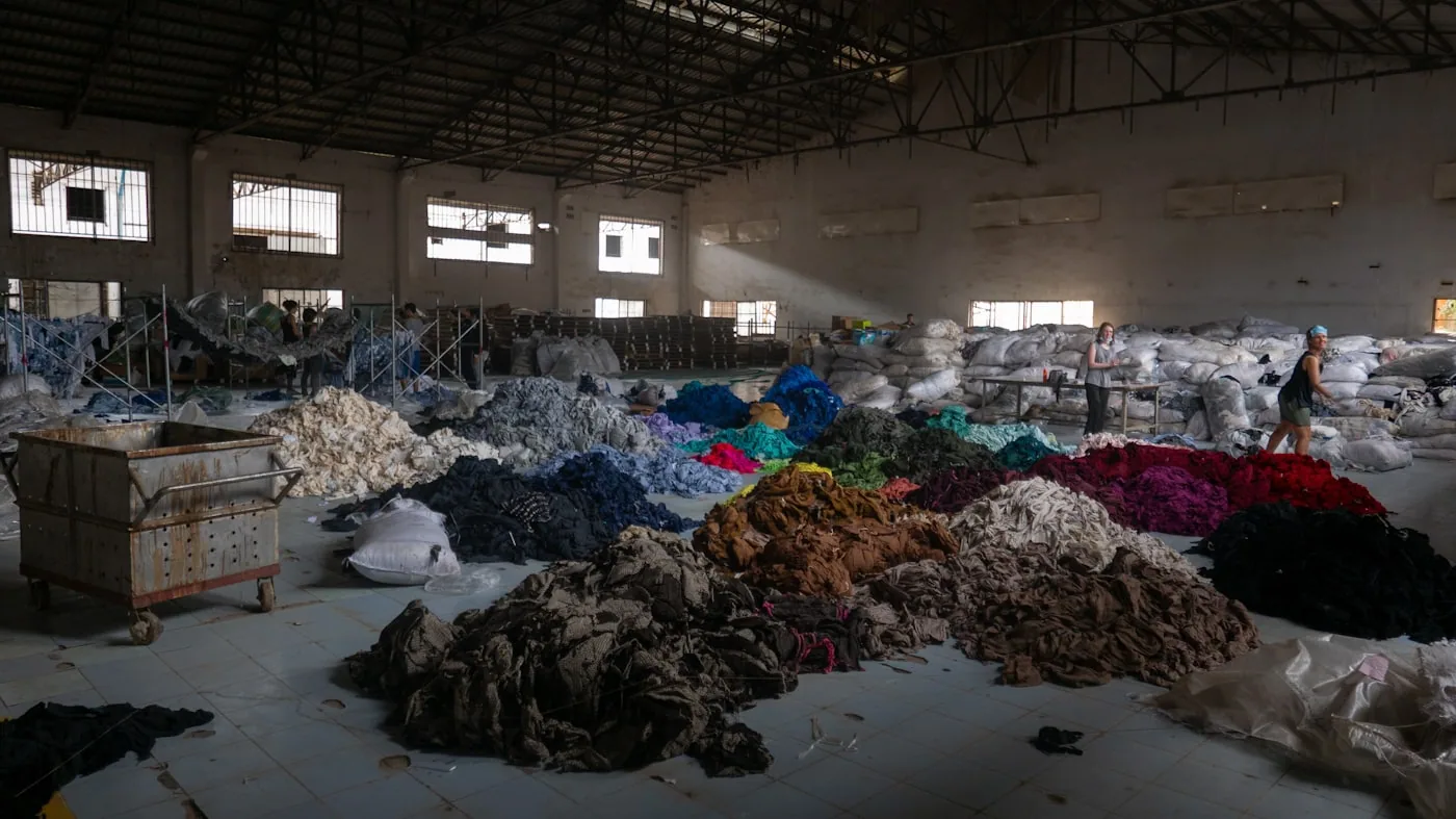 Rouleaux de jersey et molleton étiquetés, rangés sur rayonnages dans un entrepôt textile.