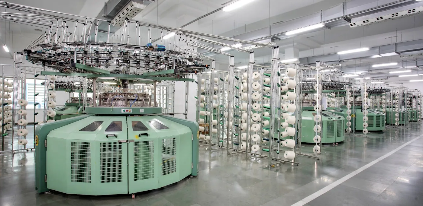 Tricoteuse rectiligne Shima Seiki en production avec opérateur réglant la machine.