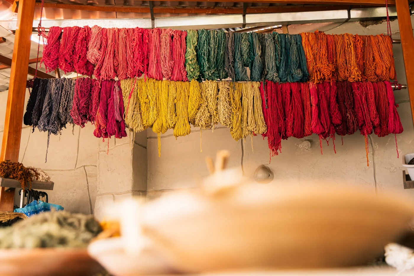 Opérateurs dans un atelier de teinture textile réglant une machine avec des rouleaux de tissu en cours de teinture.