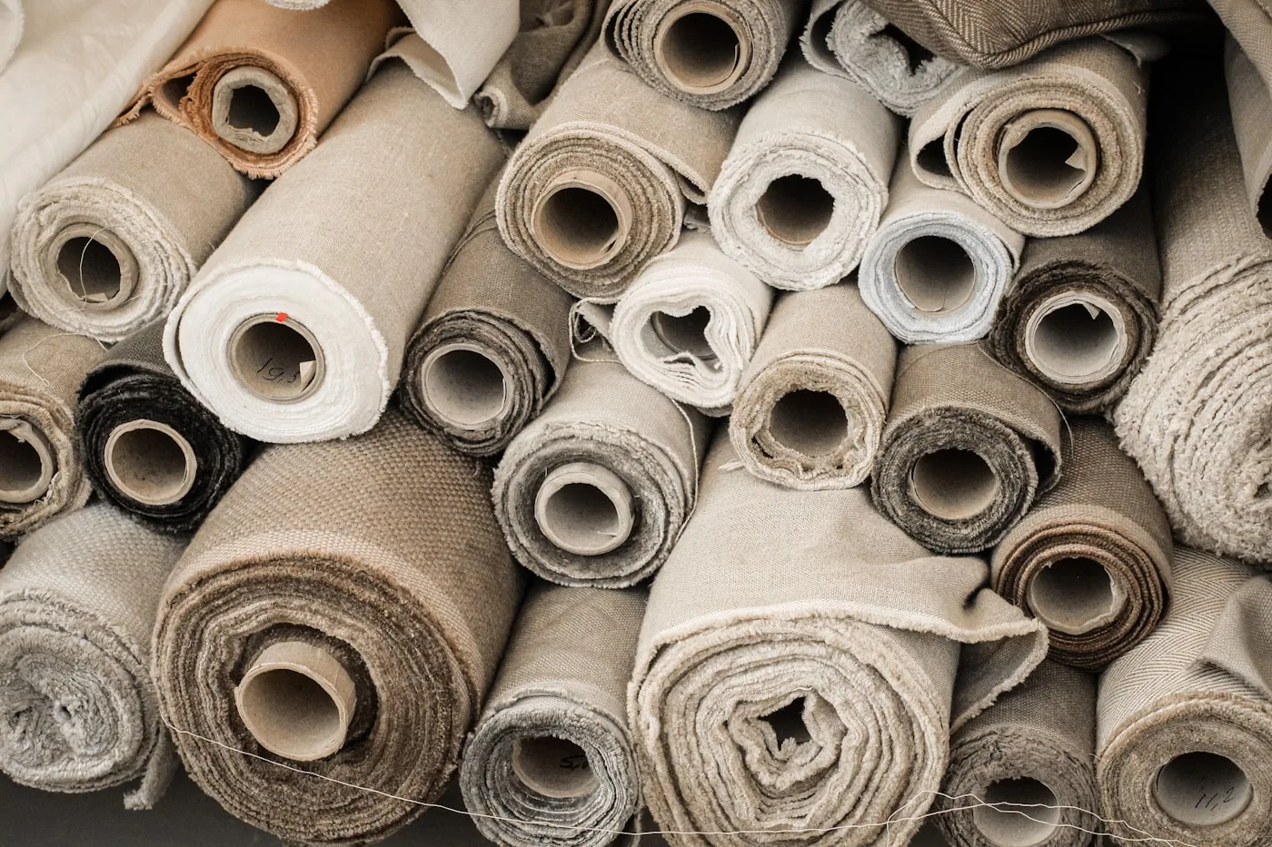 Gros plan sur des rouleaux de tissu aux armures différentes, permettant de lire la densité et la texture.