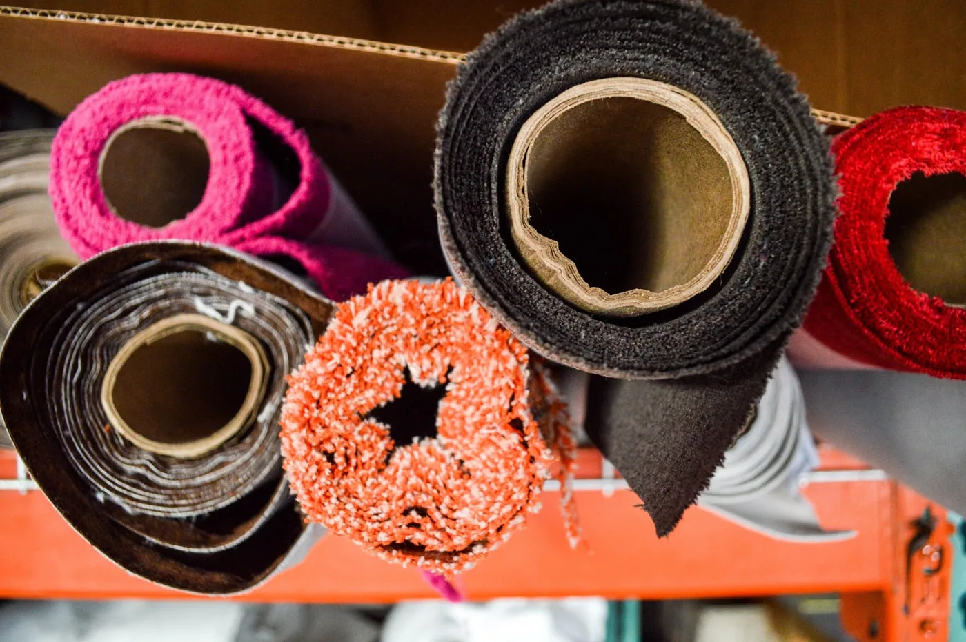Rouleaux de tissus étiquetés alignés dans un petit entrepôt textile.