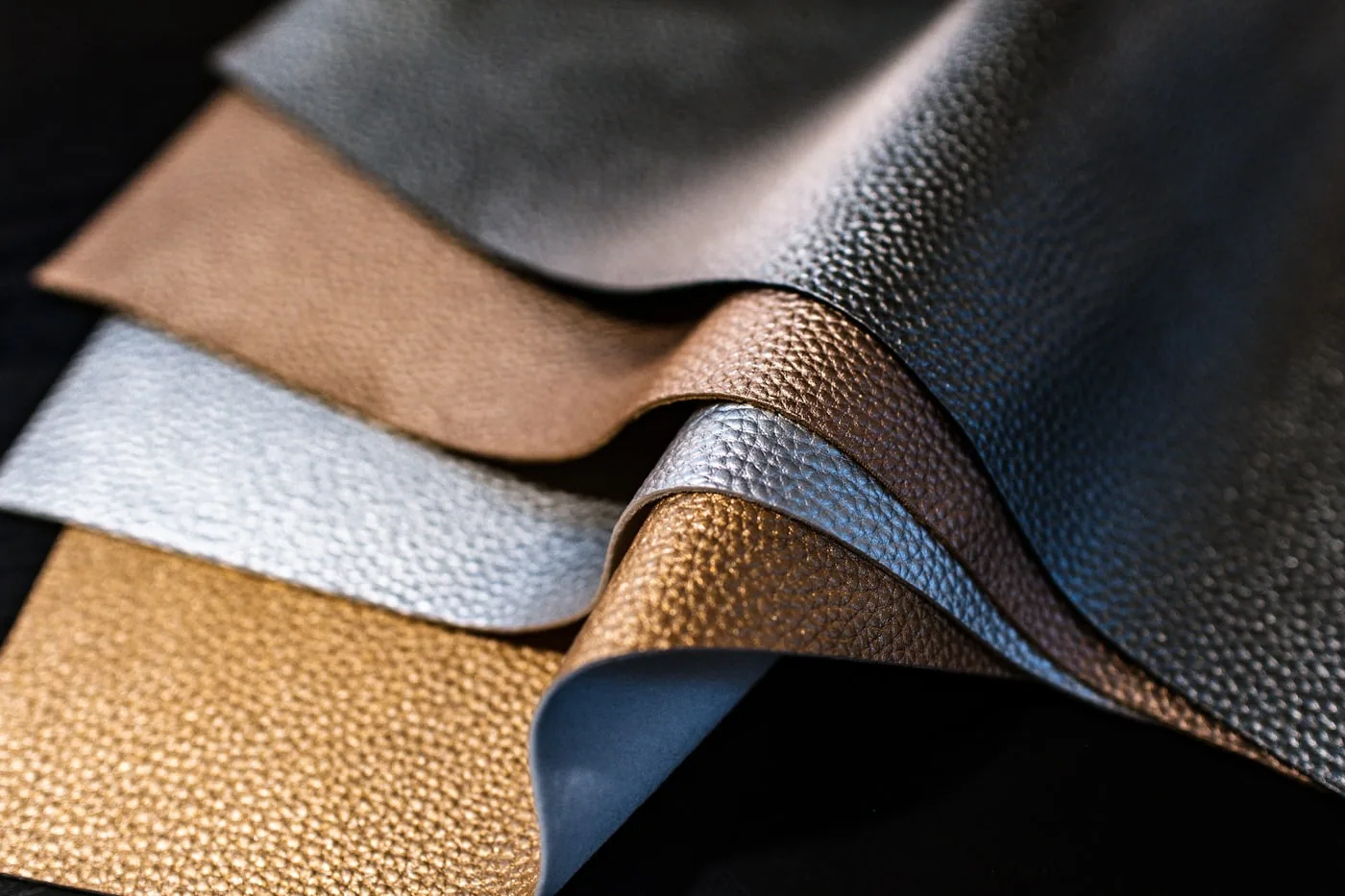 Rouleaux de simili cuir de différentes textures et épaisseurs posés sur un rayonnage d’atelier.