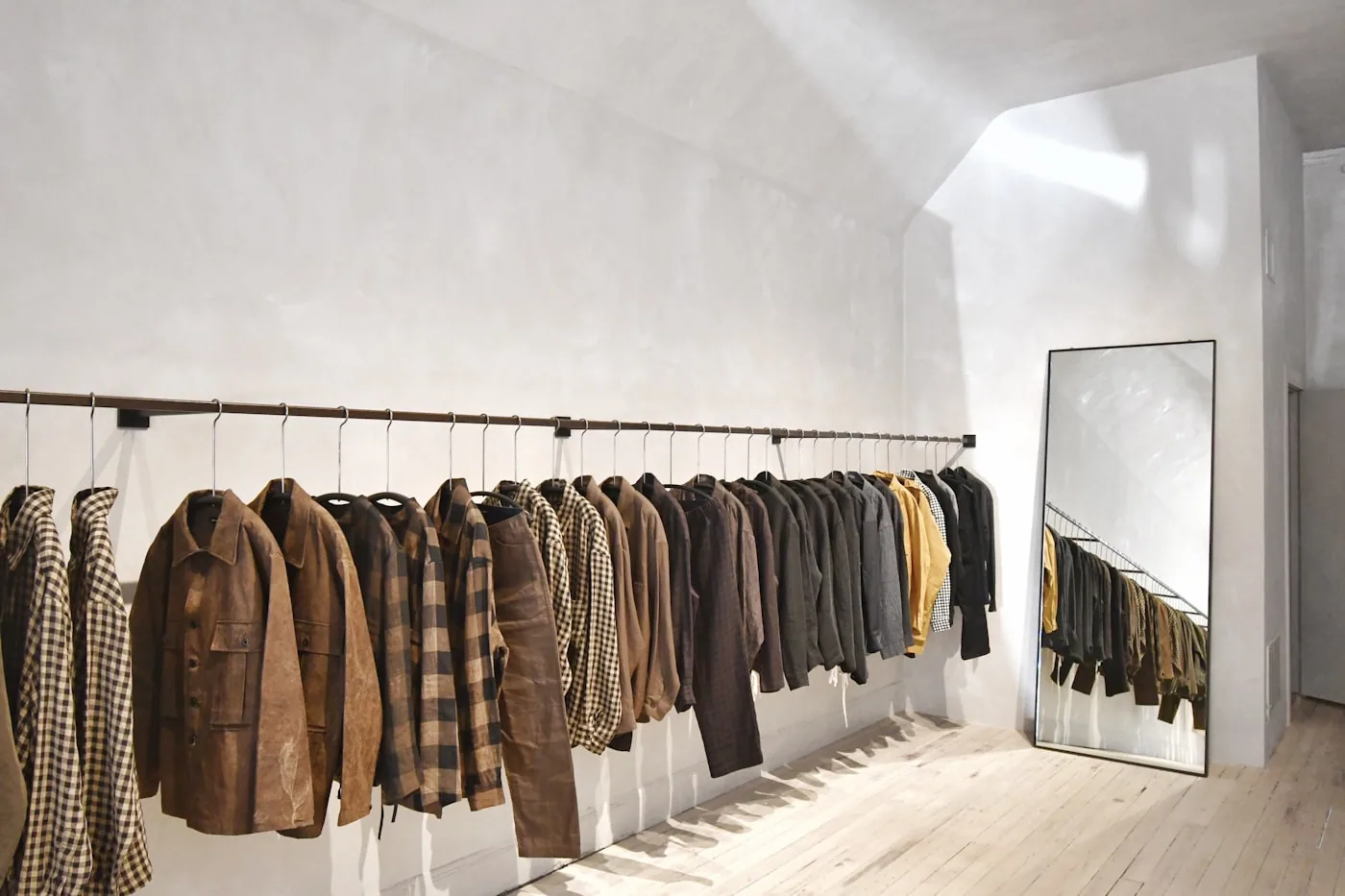 Cabines d’essayage d’une boutique avec une conseillère observant une cliente qui essaie une veste.