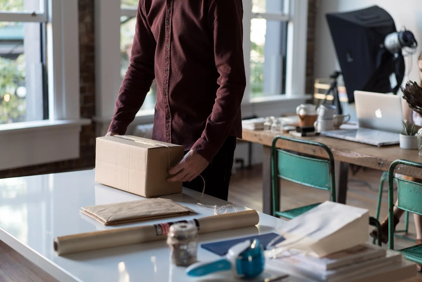 Poste d’emballage e-commerce avec cartons, scanner et vêtements pliés prêts à expédier.