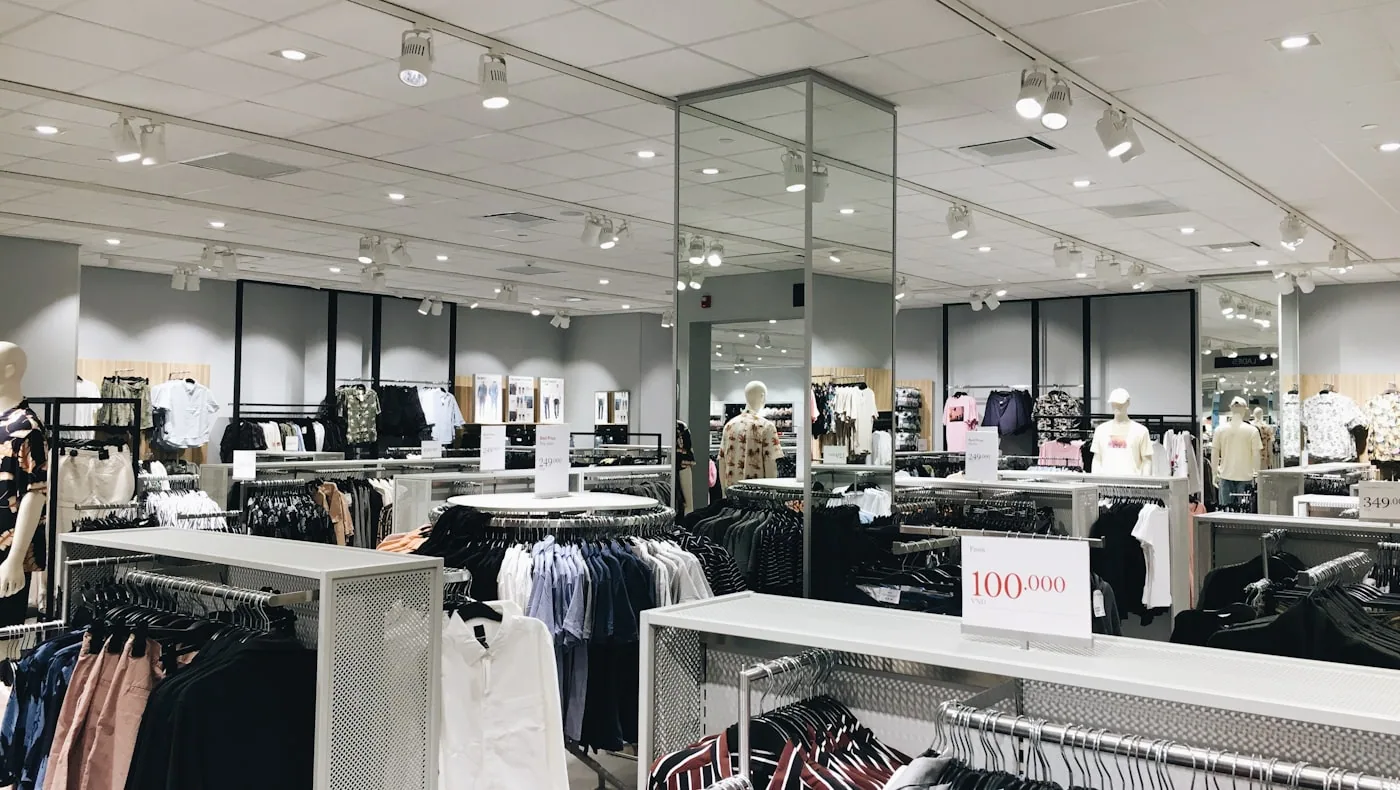 Intérieur d’un pop-up mode avec portant de vêtements, cabines improvisées et signalétique claire.
