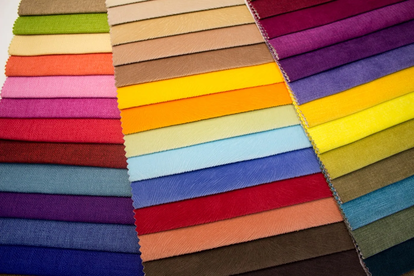 Allée d’un salon professionnel textile avec stands de fabricants et rouleaux d’échantillons.