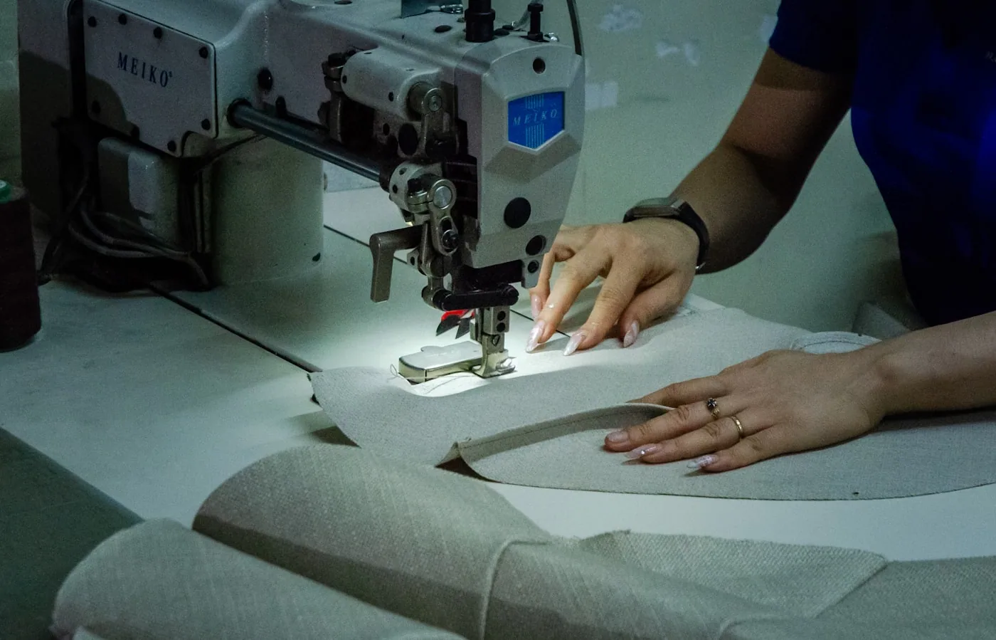 Opératrice utilisant une machine flatlock pour assembler une couture sur un tissu technique.