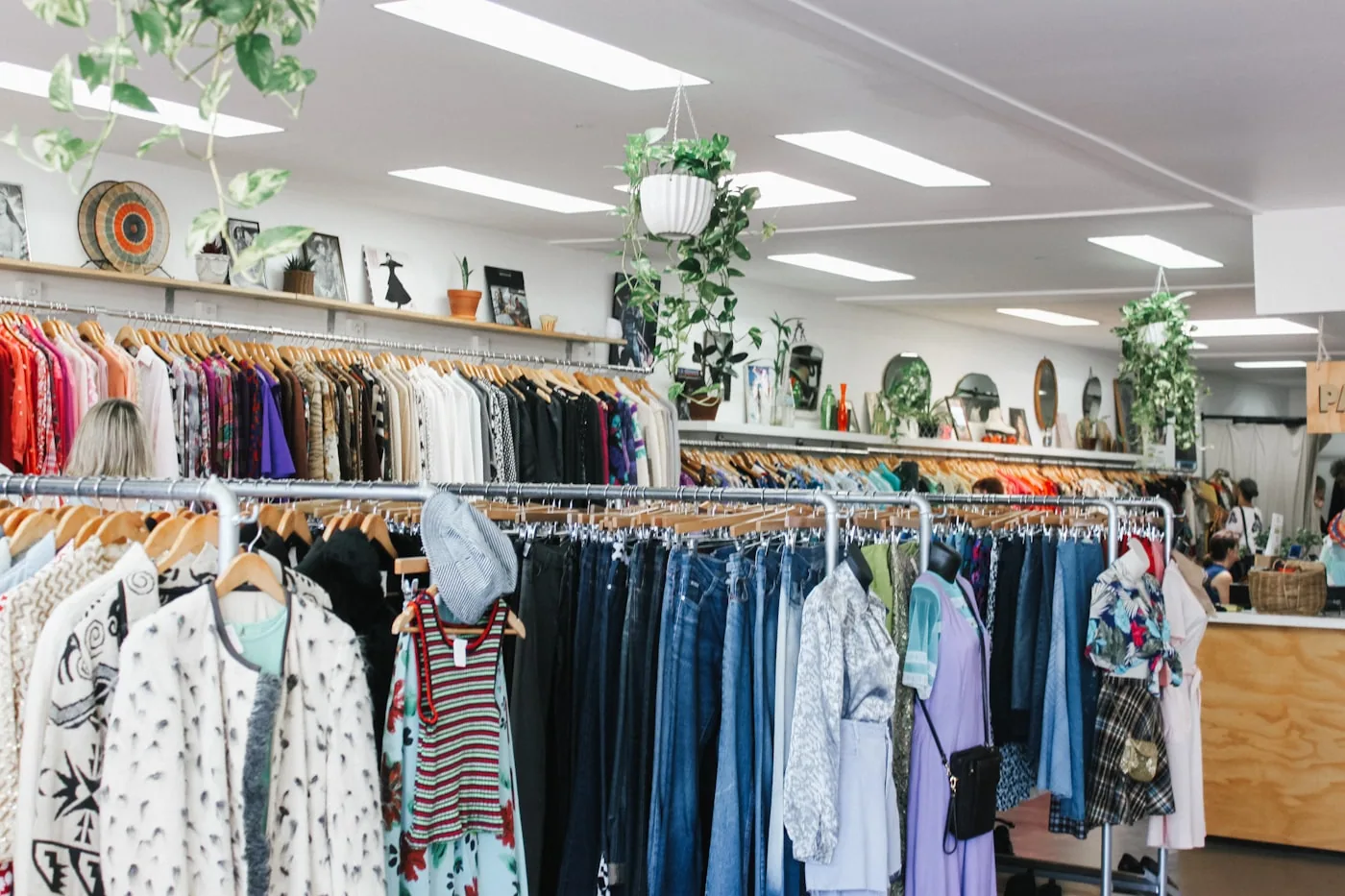 Petit pop-up de vêtements avec portants, cabine improvisée et clients essayant une pièce.